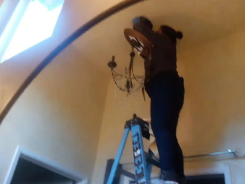 Electrician installing a chandelier in a Joliet residence